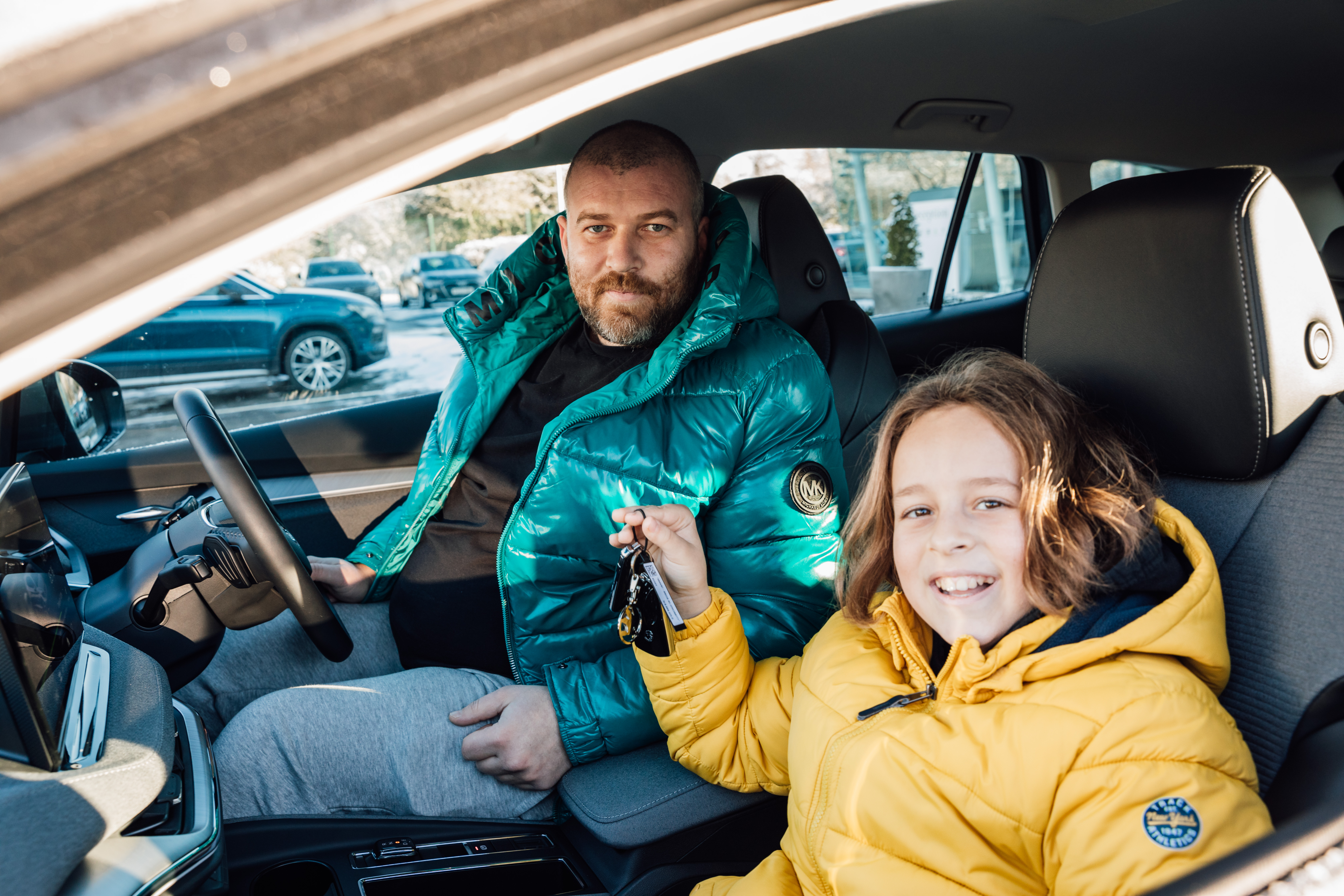 man and child in car smiling with keys